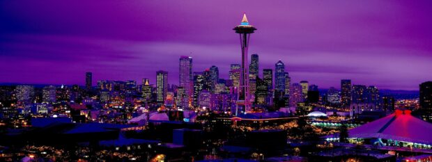 The Seattle skyline shows brightly lit buildings under a purple night sky with the Space Needle prominently featured, 2K Desktop Wallpaper
