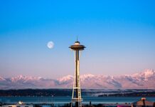 The Seattle skyline features the iconic Space Needle with snowy mountains and a full moon in the background, 4K Desktop Wallpaper
