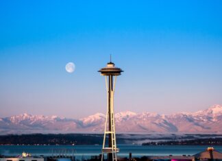 The Seattle skyline features the iconic Space Needle with snowy mountains and a full moon in the background, 4K Desktop Wallpaper