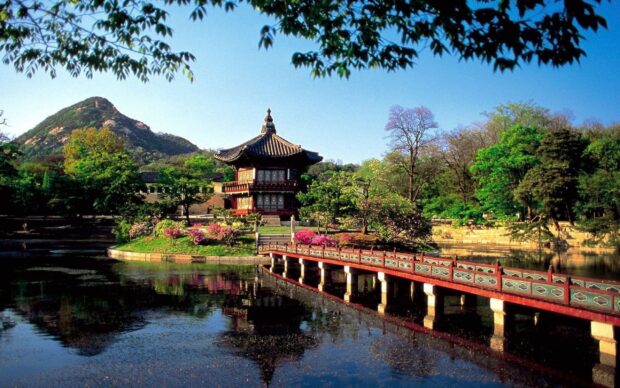 Traditional Korean pavilion in Seoul Korea surrounded by trees and flowers near a calm lake