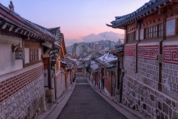 Traditional Seoul Korea street with modern city skyline in the background at sunset