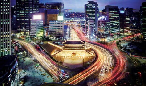Night view of ancient Seoul city gate surrounded by modern buildings and busy traffic in Seoul Korea