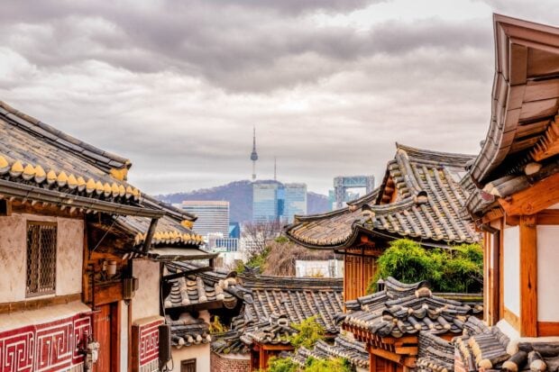 Traditional Seoul Korea houses with modern city skyline in the background under cloudy sky