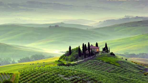 A peaceful countryside with green hills and a house surrounded by trees under soft light, 4K Desktop Wallpaper