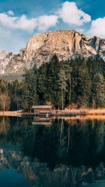A peaceful mountain lake reflects tall trees and rocky cliffs under a blue sky in this mountain lake image, 4K Mobile Wallpaper