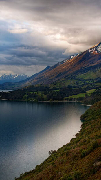 A serene mountain lake with surrounding hills under cloudy skies, HD Phone Wallpaper