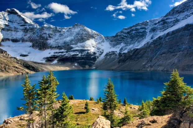 A peaceful mountain lake reflects the snowy peaks and green trees, HD Desktop Wallpaper