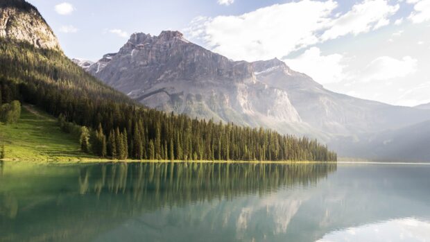 A tranquil mountain lake with lush pine trees and rugged peaks under a cloudy sky, 4K Desktop Wallpaper