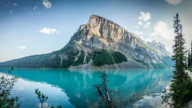 A clear mountain lake reflects the towering rocky peak under the blue sky, 4K Desktop Wallpaper