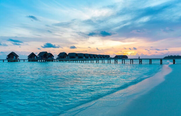 A calm sea surrounds the tropical bungalow villas during a beautiful sunset, HD Desktop Wallpaper