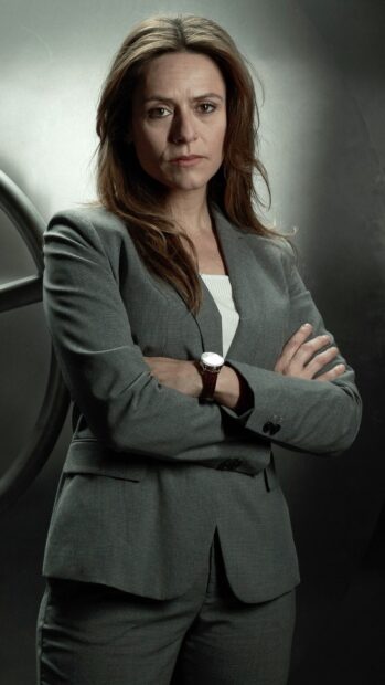 A serious woman in a gray suit stands with crossed arms appearing confident in Money Heist Wallpapers, 4K Mobile Wallpaper