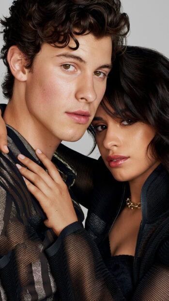 Close up of Shawn Mendes posing with a woman wearing black outfits