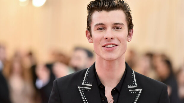 Shawn Mendes smiling warmly in a black studded jacket at a public event