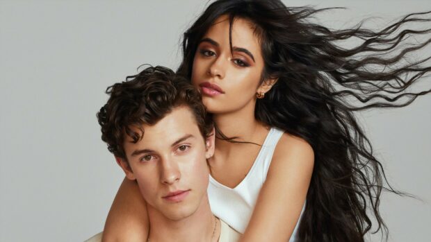 Shawn Mendes with a woman posing closely with flowing hair in a studio setting