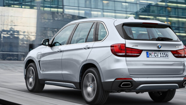 A silver BMW X5 is driving past a modern building with its brake lights visible, 4K PC Wallpaper
