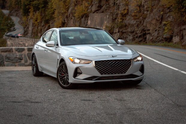 A silver Genesis car is parked on a mountain road with autumn trees in the background, 2K Desktop Wallpaper