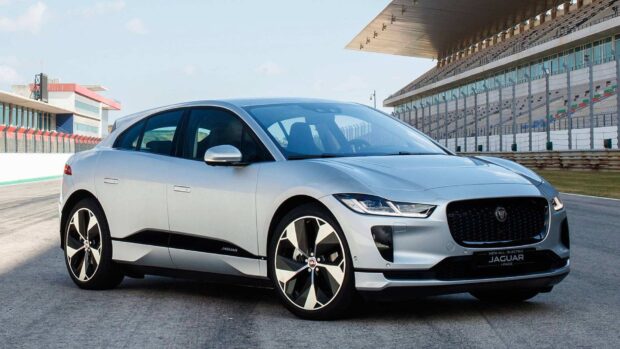 A silver Jaguar I Pace electric vehicle is parked on a racing circuit under clear sky, HD Desktop Wallpaper