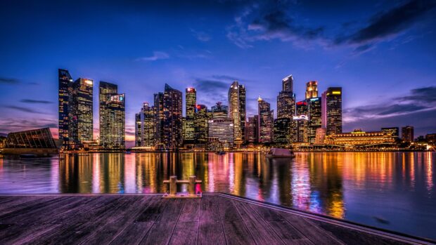 Singapore skyline at dusk featuring illuminated skyscrapers and reflections on the water