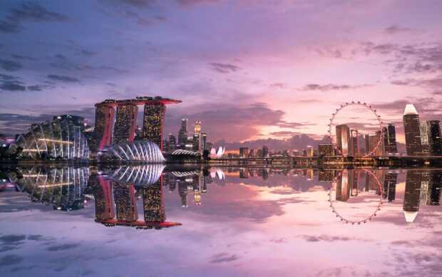 Stunning Singapore skyline with illuminated buildings and a giant ferris wheel at sunset