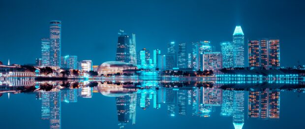 A panoramic view of Singapore skyline with illuminated skyscrapers reflected on calm water at night