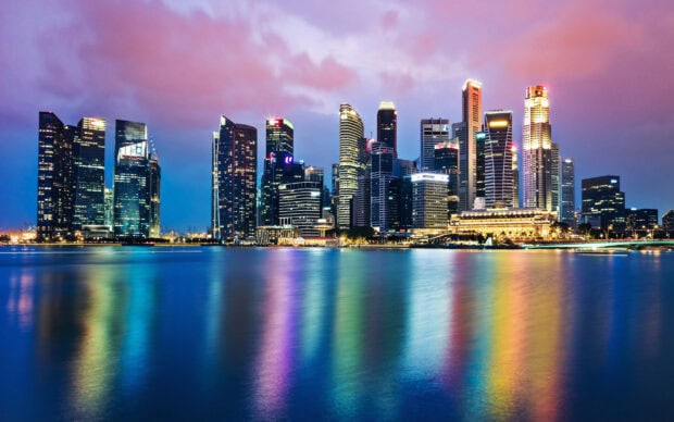 Beautiful Singapore skyline with skyscrapers reflecting on calm water during sunset