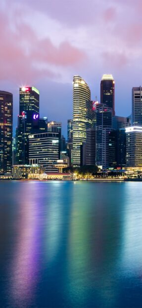 Modern Singapore skyline towers reflecting colorful lights on the water at dusk