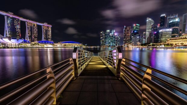 A night view of Singapore skyline with a lit bridge leading towards the city buildings