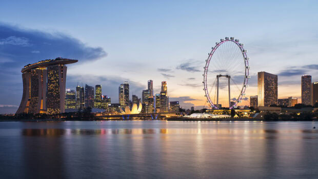 The Singapore skyline features iconic architecture and landmarks during dusk with city lights reflecting on water
