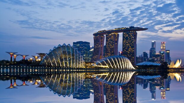 The Singapore skyline features iconic architecture and modern buildings reflecting over calm water at dusk