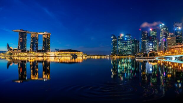 Night view of Singapore skyline reflecting on water with Marina Bay Sands and city buildings