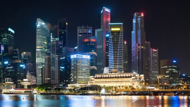 Night view of Singapore skyline with illuminated buildings reflecting on water