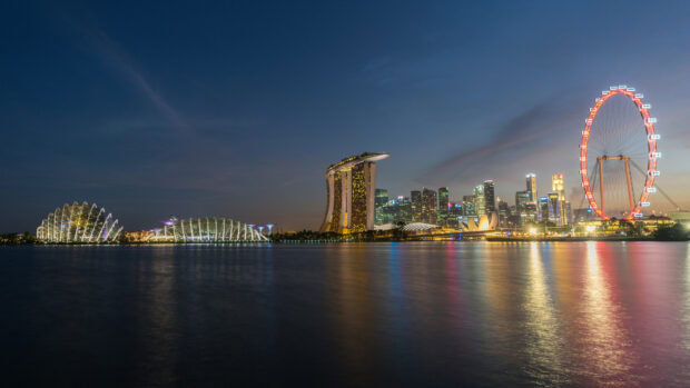 A beautiful Singapore skyline with iconic buildings and city lights reflecting on the water at dusk
