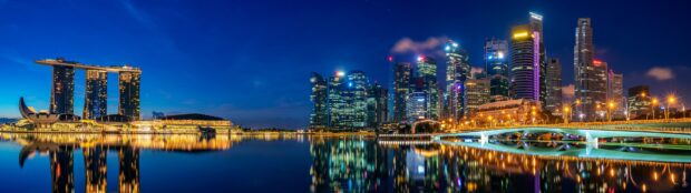 Singapore skyline viewed at night with illuminated buildings reflected on calm water