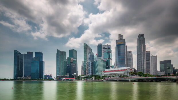 Singapore skyline with modern high rise buildings under cloudy sky and calm water