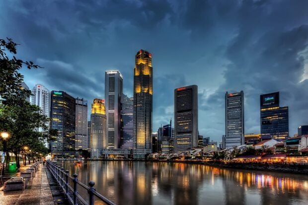 Evening view of Singapore skyline with high rise buildings reflecting on river water