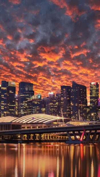 The Singapore skyline with dramatic clouds and reflections on the water during sunset
