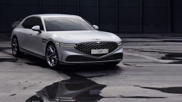 A sleek silver Genesis car is parked on a wet surface under dim lighting showcasing Genesis Wallpapers, HD Desktop Wallpaper