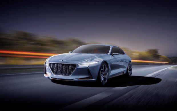 A sleek Genesis car displayed in motion on the road at dusk, 2K Desktop Wallpaper