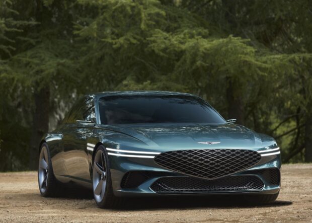 A sleek Genesis car is parked on a dirt road surrounded by trees in this image, 2K Desktop Wallpaper