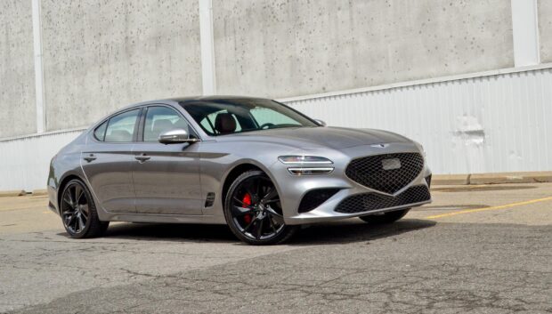 A sleek metallic gray Genesis car is parked on an urban pavement near a concrete wall showing its stylish design, HD Desktop Wallpaper