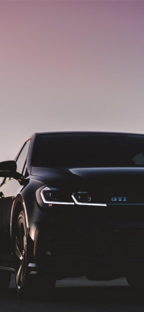 Một chiếc Golf Gti màu đen bóng bẩy được chụp từ phía trước với đèn pha bật sáng lúc hoàng hôn, Hình nền điện thoại 2K