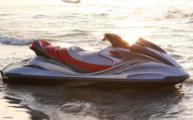 A sleek jet ski rests on calm water during sunset by the shore, HD Desktop Wallpaper