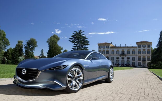 A sleek Mazda sports car is parked in front of a historic building under a clear blue sky, 2K Desktop Wallpaper