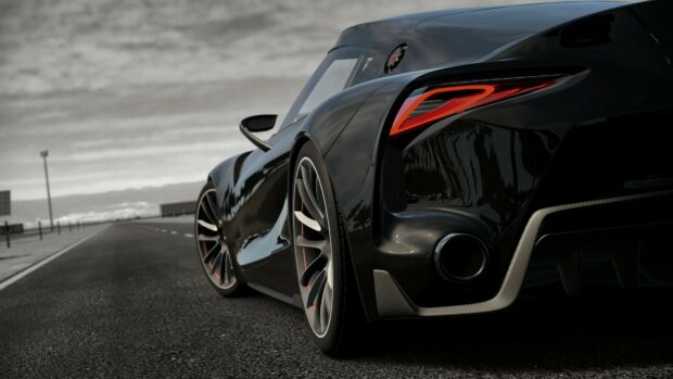 Luxury black sports car on open road with sleek aerodynamic design and modern tail lights.