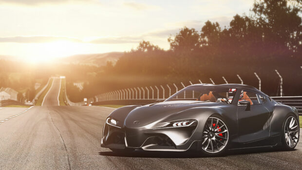 A sleek black sports car on a race track during sunset with a scenic landscape in the background.