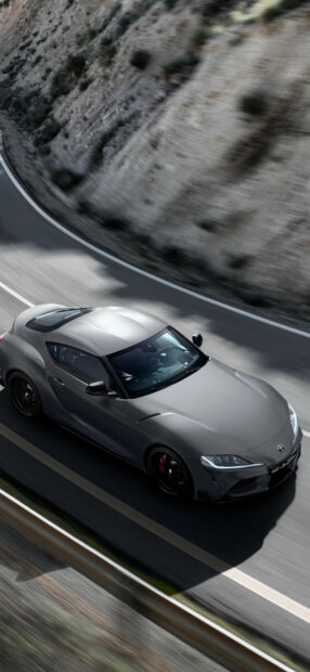 Sleek silver sports car racing on mountain road.
