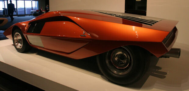 A sleek vintage Lancia car design with an orange body and unique rear features, 2K Desktop Wallpaper