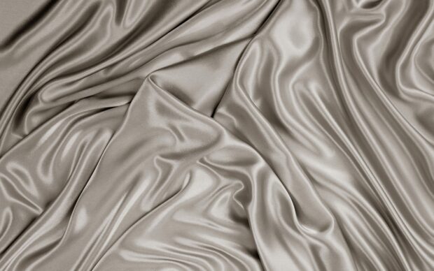 A close up of smooth silver silk fabric showing delicate folds and glossy texture, 2K Desktop Wallpaper