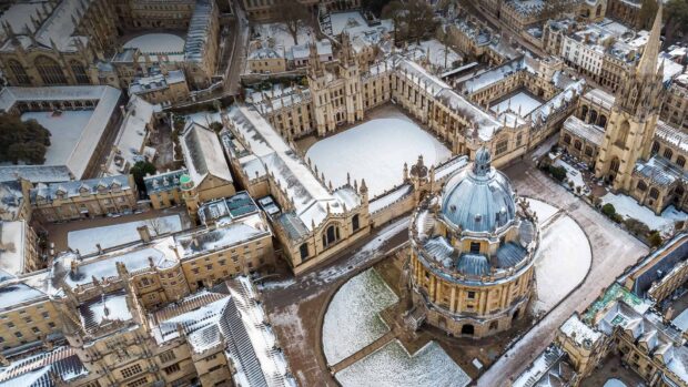 Aerial view of Oxford University covered in snow showcasing historic buildings and courtyards, HD Desktop Wallpaper