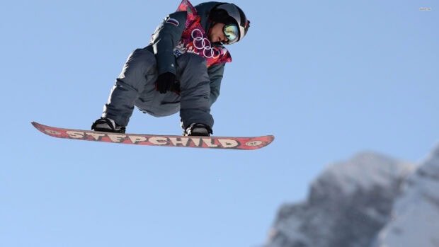 A snowboarder performing a jump in the air wearing winter gear and goggles